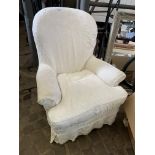 Upholstered armchair with white loose covers.