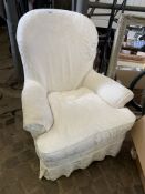 Upholstered armchair with white loose covers.