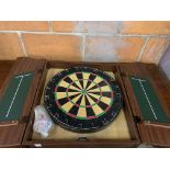 Dartboard in a wall mounted wooden case with darts.