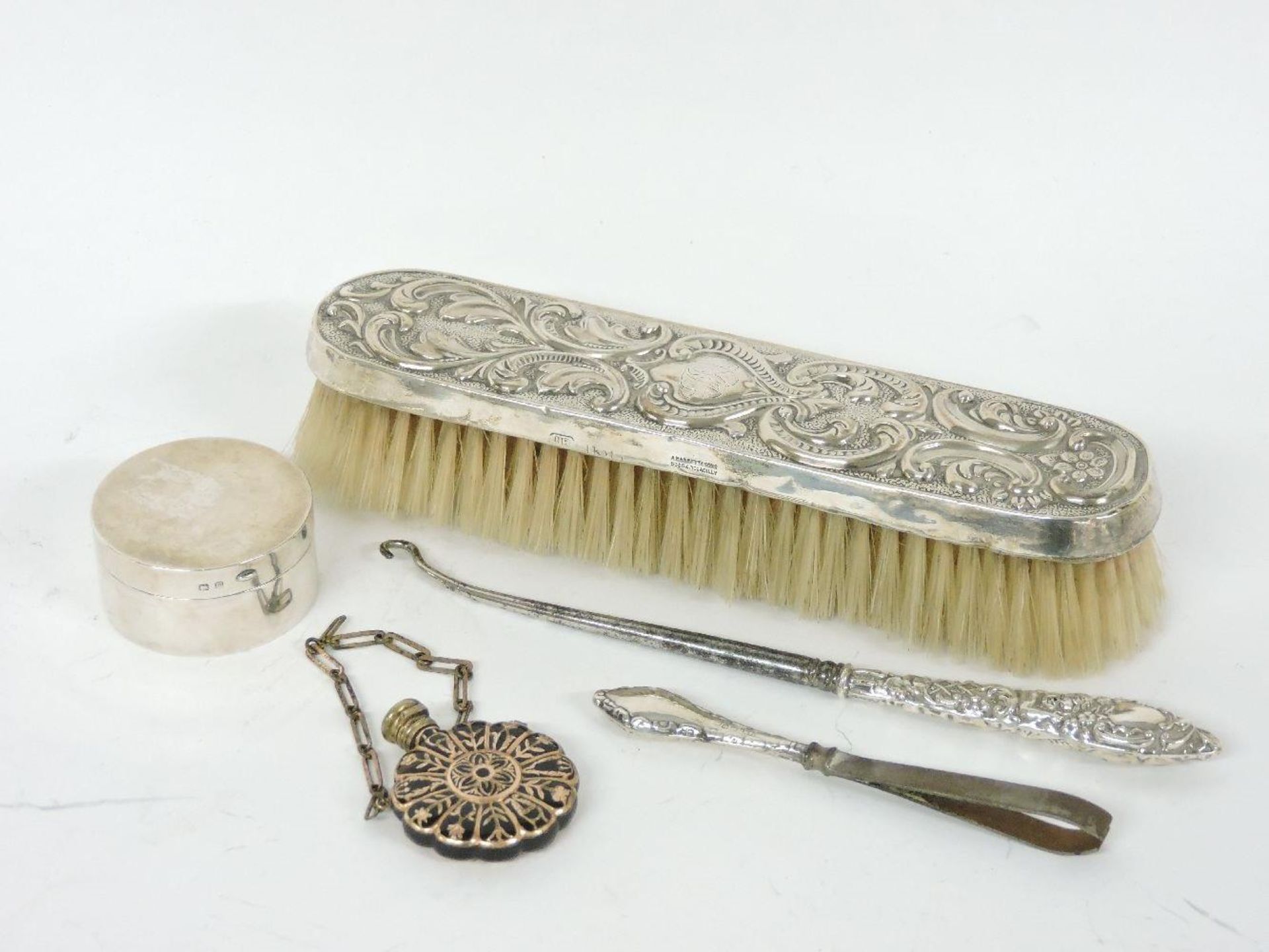 A Toledo ware scent bottle, a cylindrical silver pill pot, button hook, tweezers, and brush