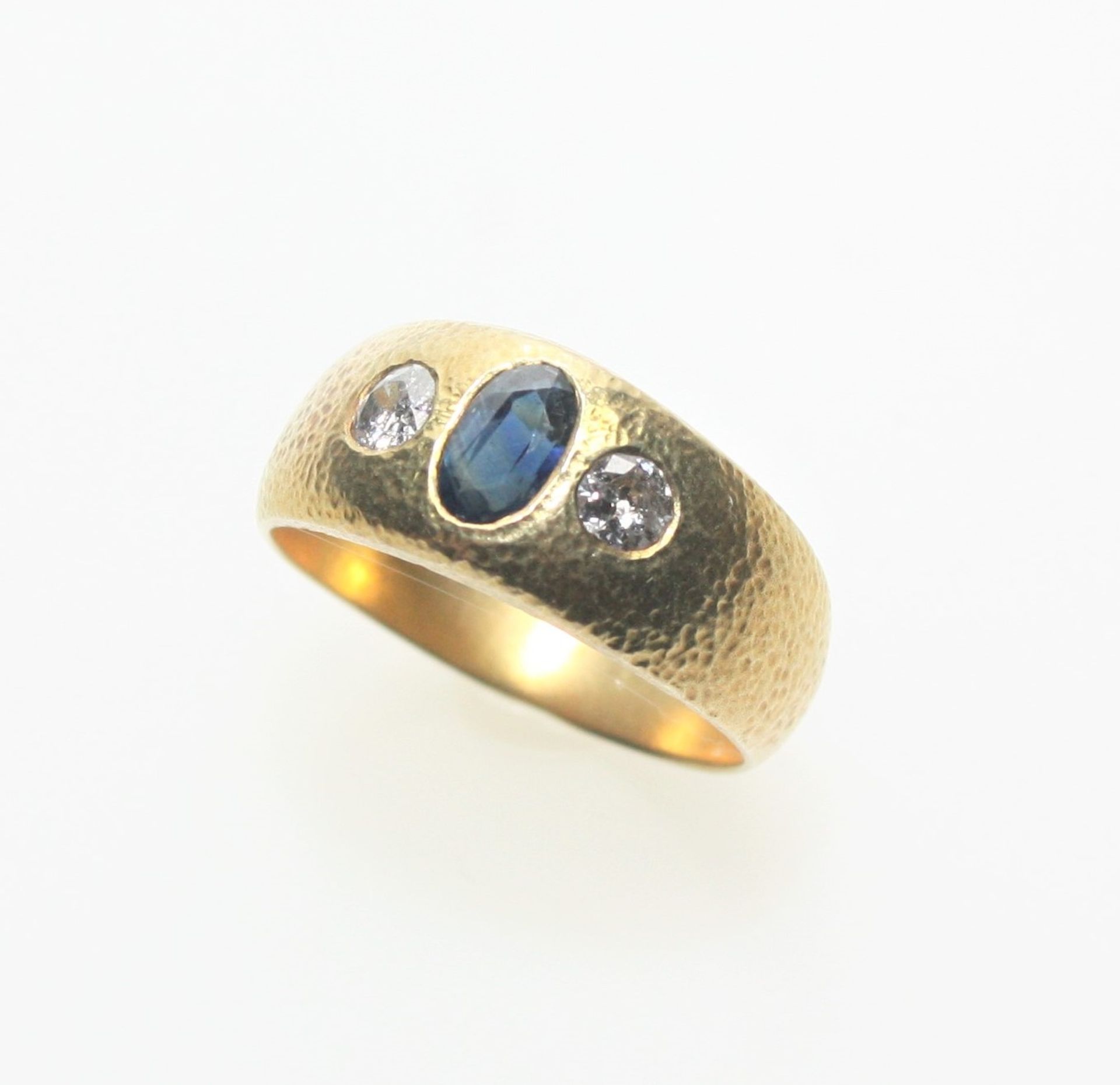 Goldener Bandring 585/f gest. mit einem oval facettierten Saphir und zwei Diamanten in
