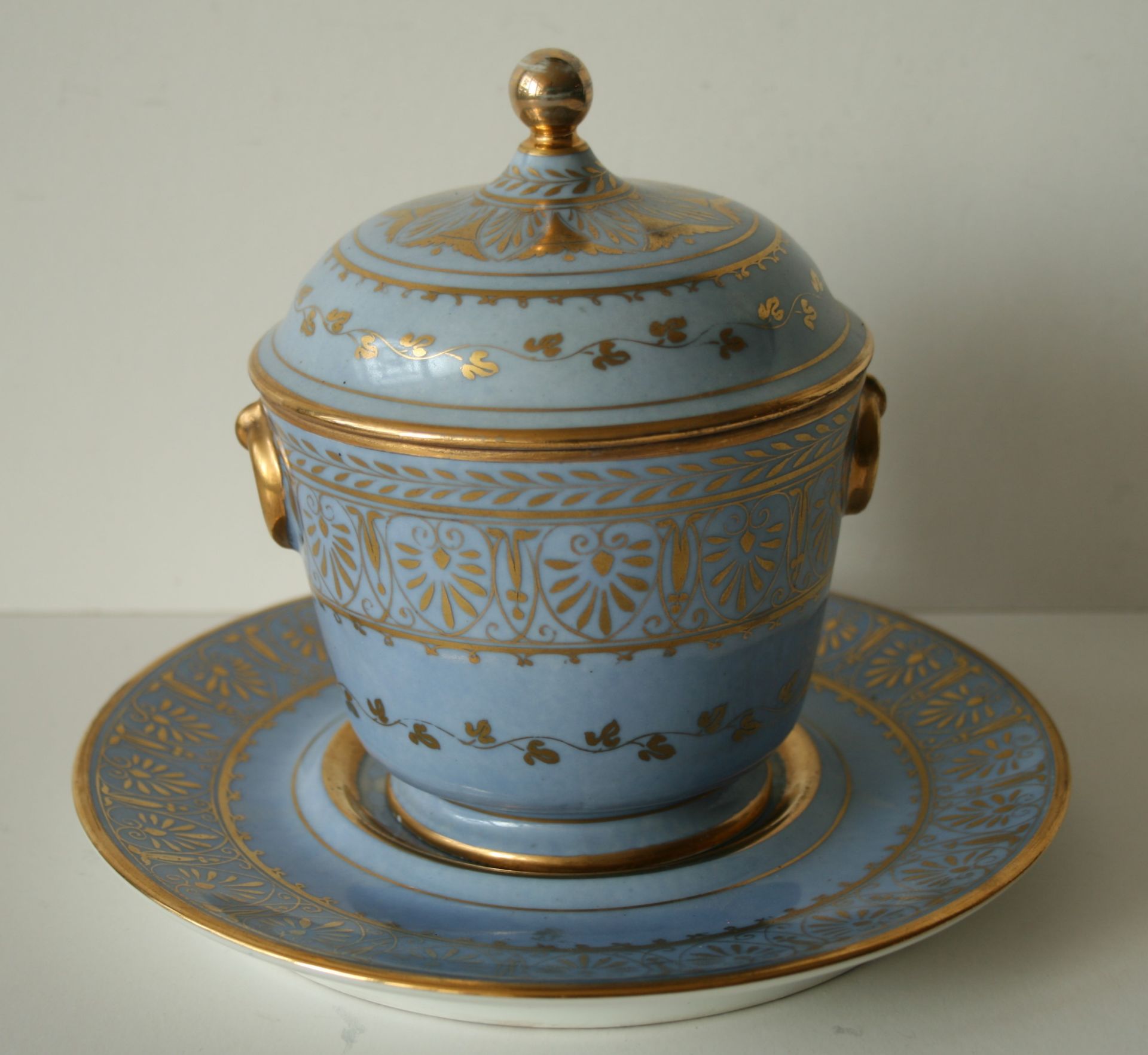 Pot couvert reposant sur une assiette en porcelaine bleue pale et rehaussé à l'or [...]