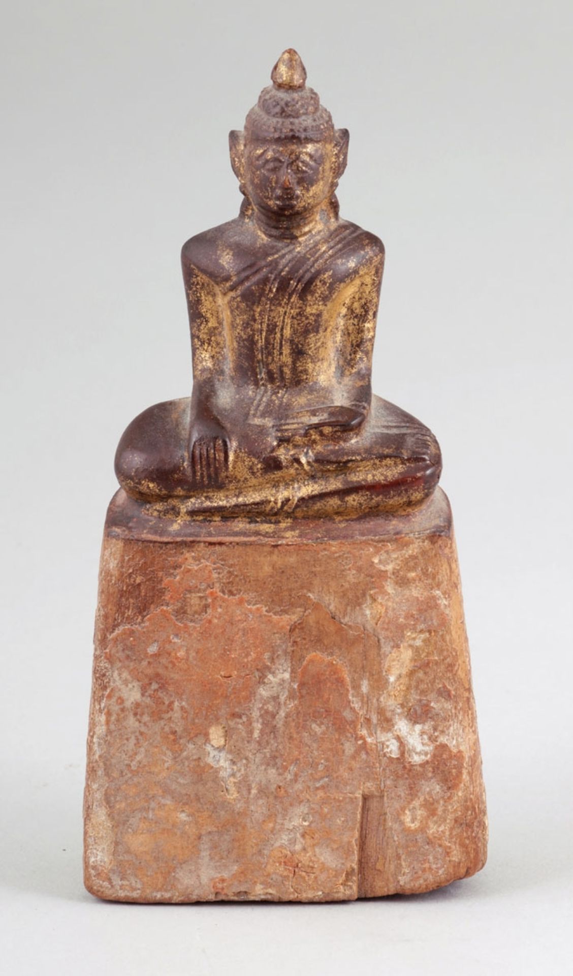BuddhaBurma, um 1900. Holz.Vergoldet. H. 15,5 cm. Auf hohem Sockel sitzend mit den Händen im Schoß.-