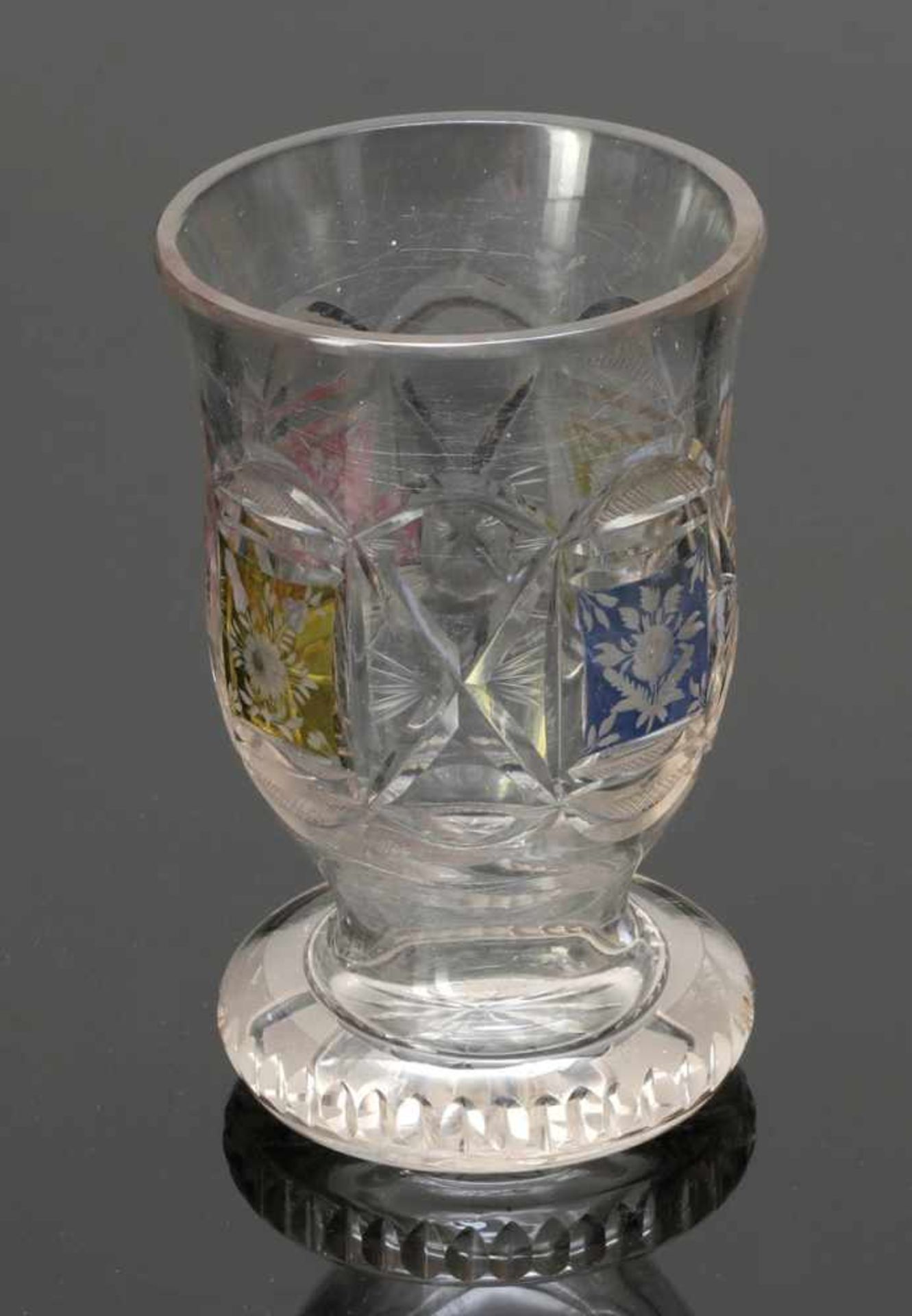 Biedermeier FußbecherUm 1850. Farbloses Glas, gelb, rot und blau lasiert. Geschliffene Blumen. H. 12