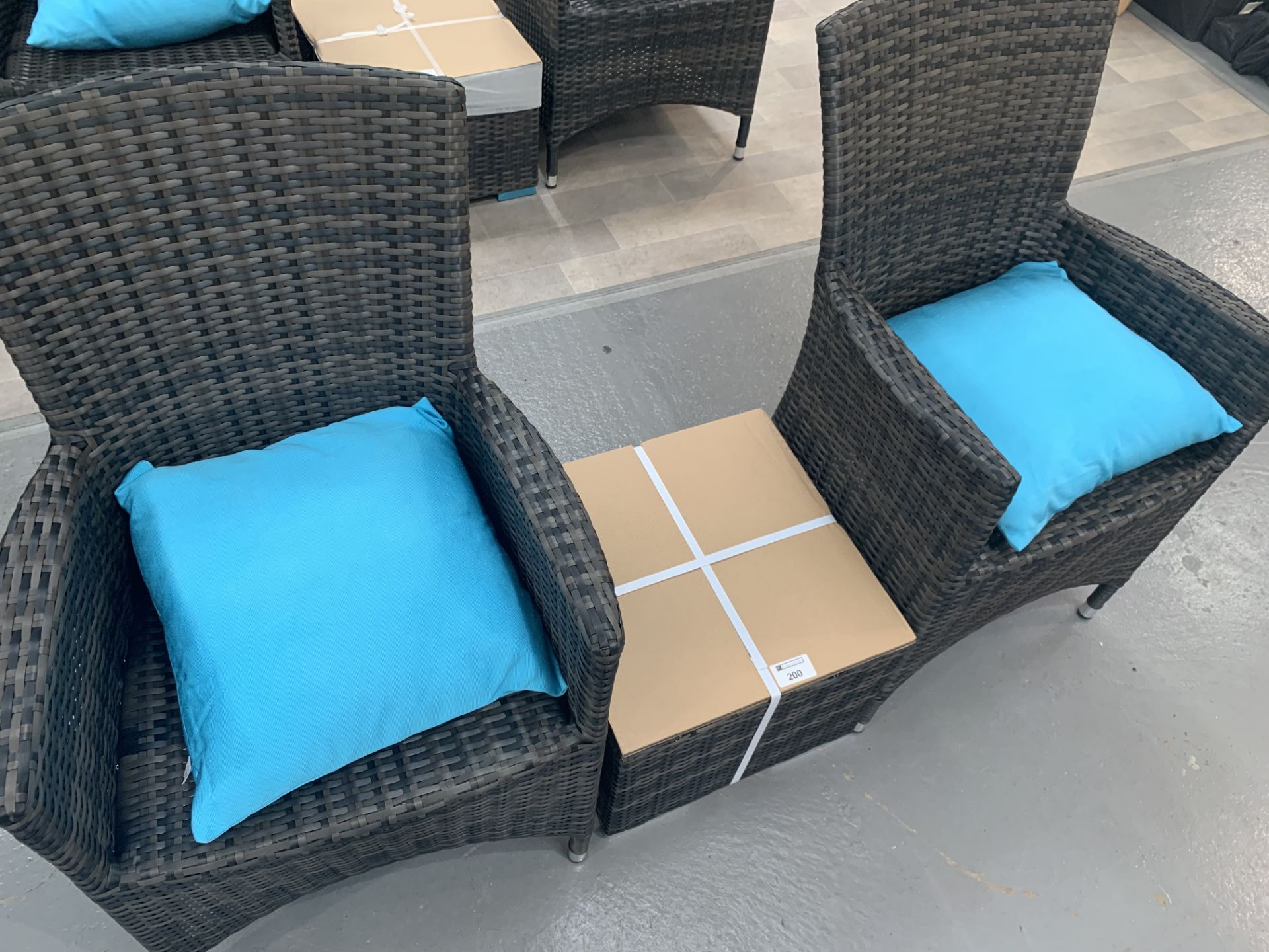 A Pair of Maze Rattan Cushion Arm chairs with matching glass top table