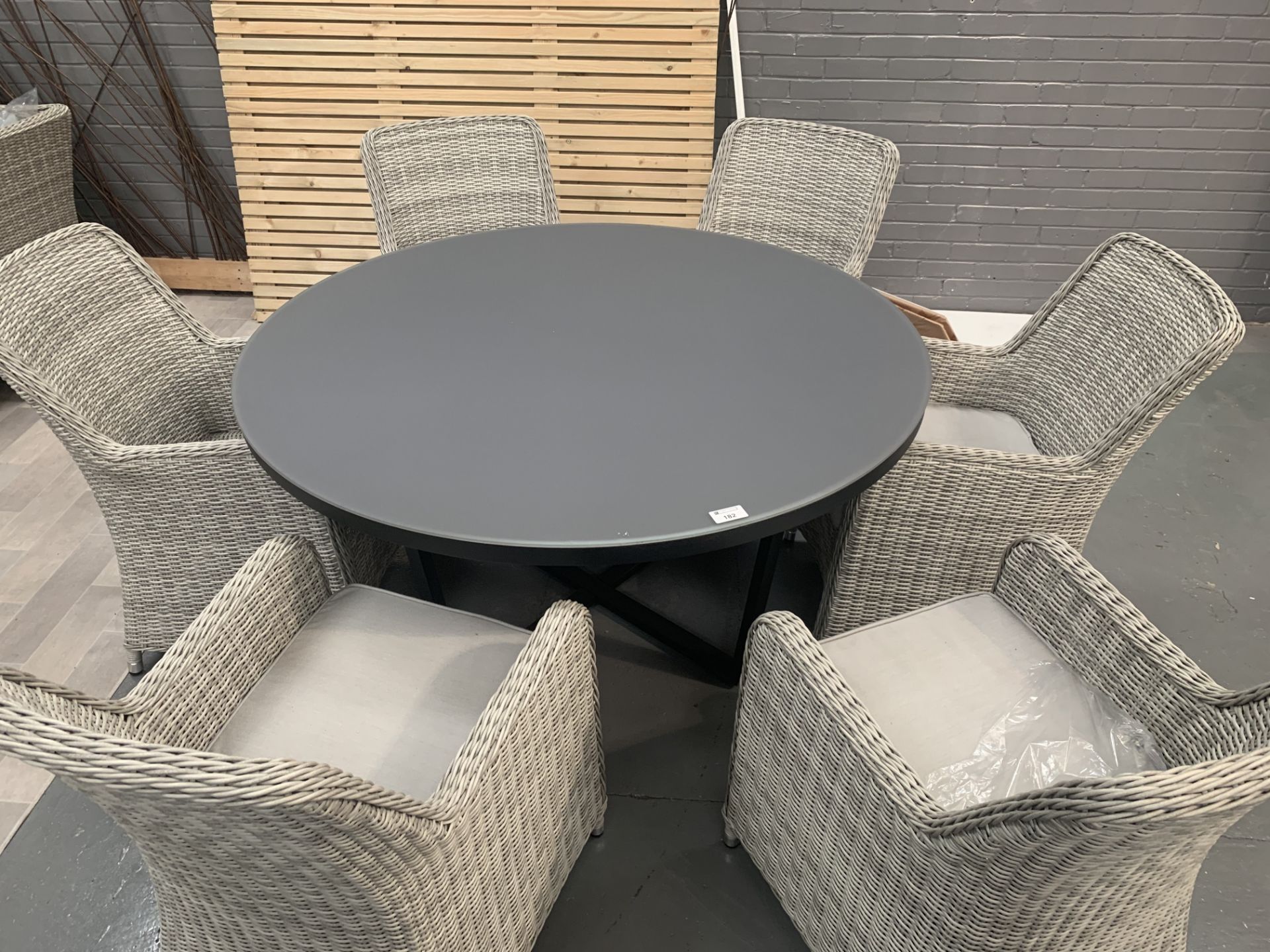 Smokey glass top table (146cm dia) on grey base with 6 x Maze Rattan arm chairs 3 with cushions