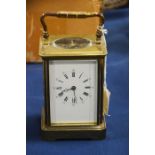 A brass cased carriage clock, enameled dial, bevel