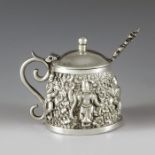 India circa 1900, a white metal mustard pot and spoon, conical form, heavily embossed and repousse d