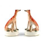 A pair of Staffordshire pottery figures of greyhounds