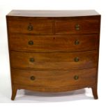 A George III bow fronted mahogany chest of two short over three long cockbeaded drawers