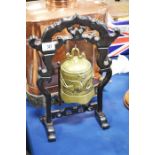 A brass temple bell on pierced wooden stand.
