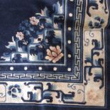 A Chinese silk rug, salmon pink, blue and white flowers and leaves to a dark blue ground