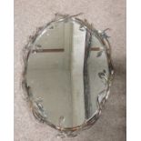 An oval metal framed wall mirror, decorated with l