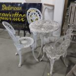 Three cast metal patio chairs and a circular cast