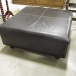 A Calia black leather footstool on wooden feet.