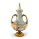 A Shuck, for Royal Worcester, a twin handled vase and cover, circa 1924, painted with a stalk