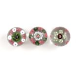 Clichy, three patterned millefiori paperweights ,one with central deep red and white cane, surrounde