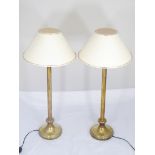 A pair of brass table lamps with cream colour shades,