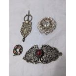 A Middle Eastern silver belt buckle together with three other silver brooches