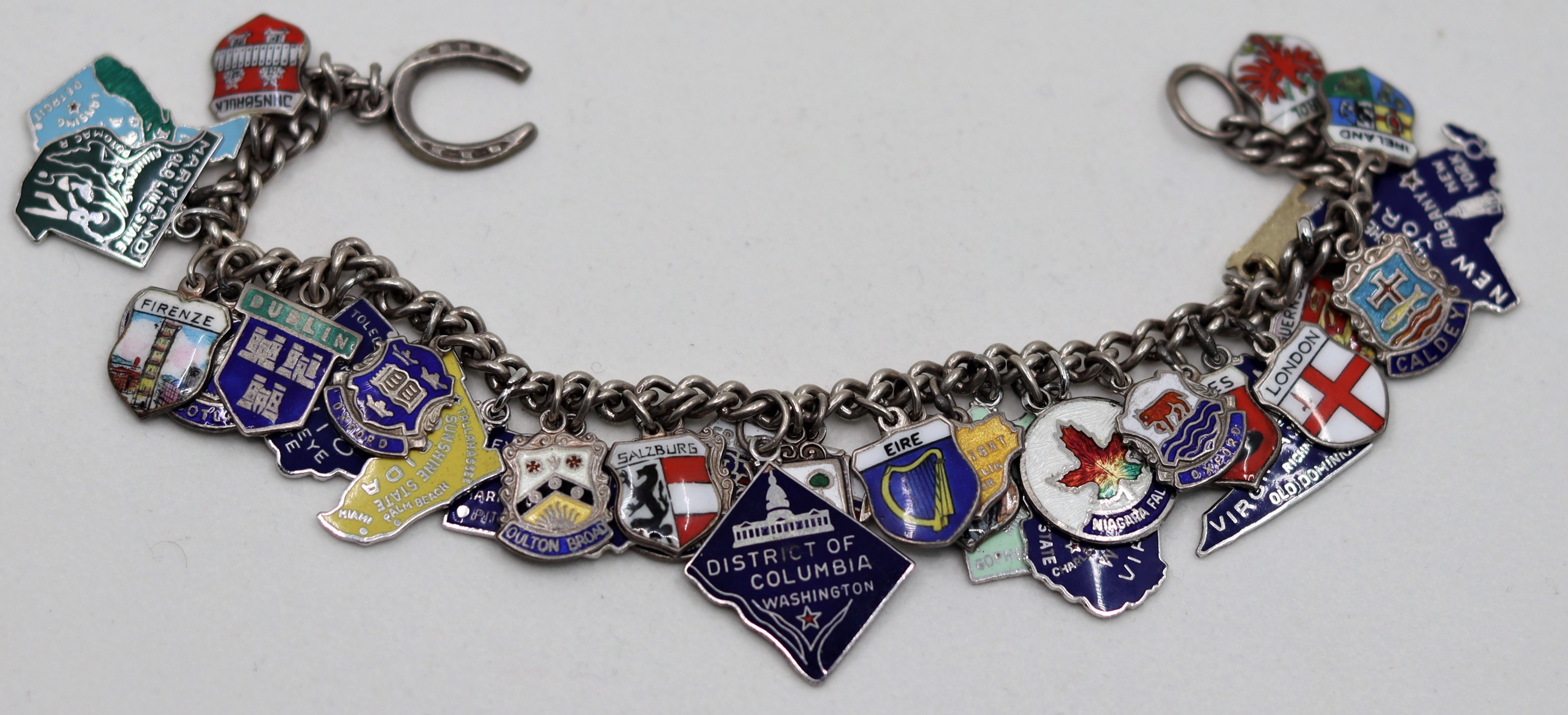 A silver chain charm bracelet with multiple city charms, various marks, total weight 59.7g