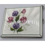 A silver guilloche enamel compact depicting flowers, the rear side with an engine turned finish, the