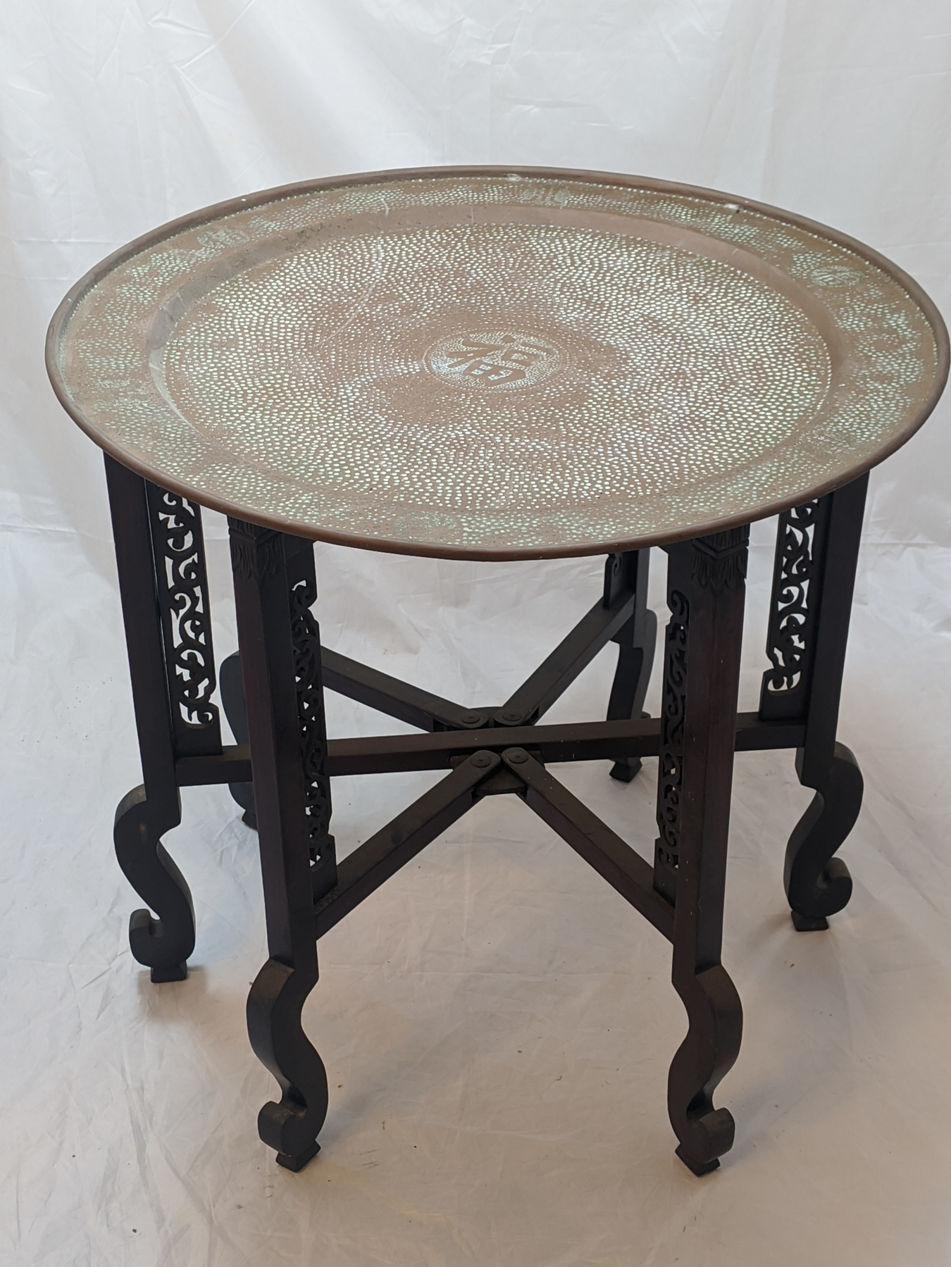 A Chinese folding tables with circular copper top, carved and pierced legs