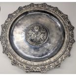 A Russian white metal dish with elaborate border and a central St.Nicholas, 700g, D.34.5cm