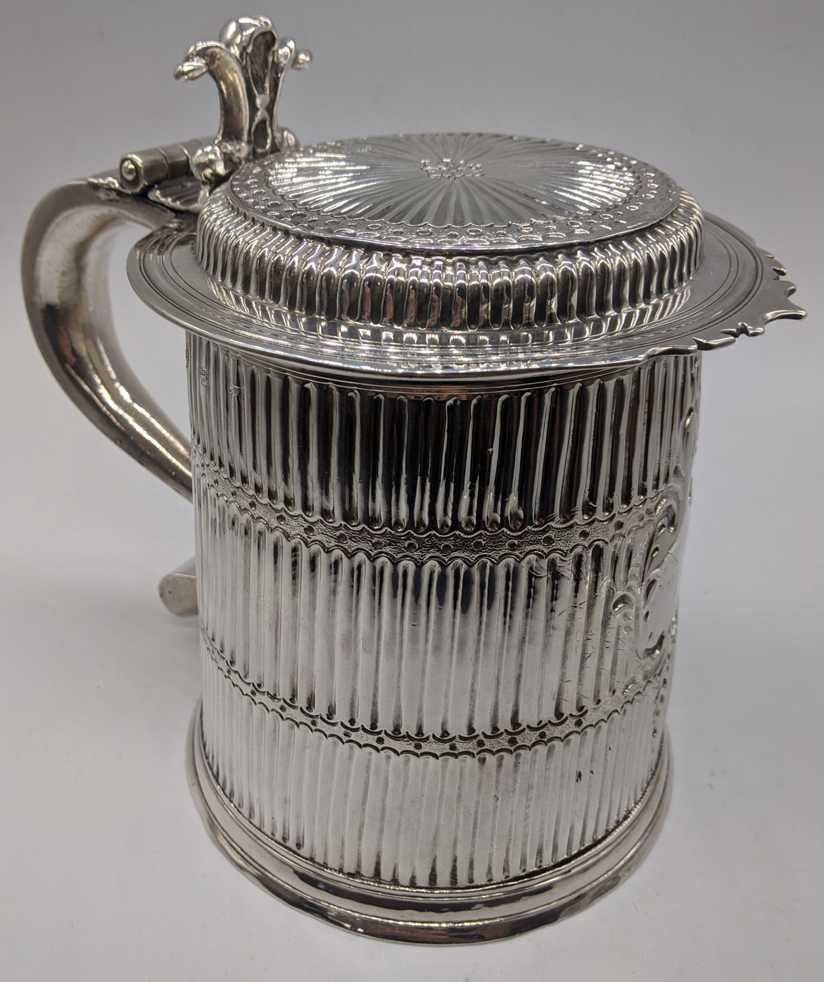 A William III silver tankard with flat top lid, S-shape handle and scrolling thumbpiece, the