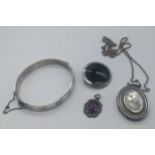 A collection of silver jewellery to include a bangle, a locket, a pendant with purple stone and a