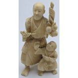 A late 19th century Japanese ivory study of a father with his son holding a pipe and sprig of fruit,