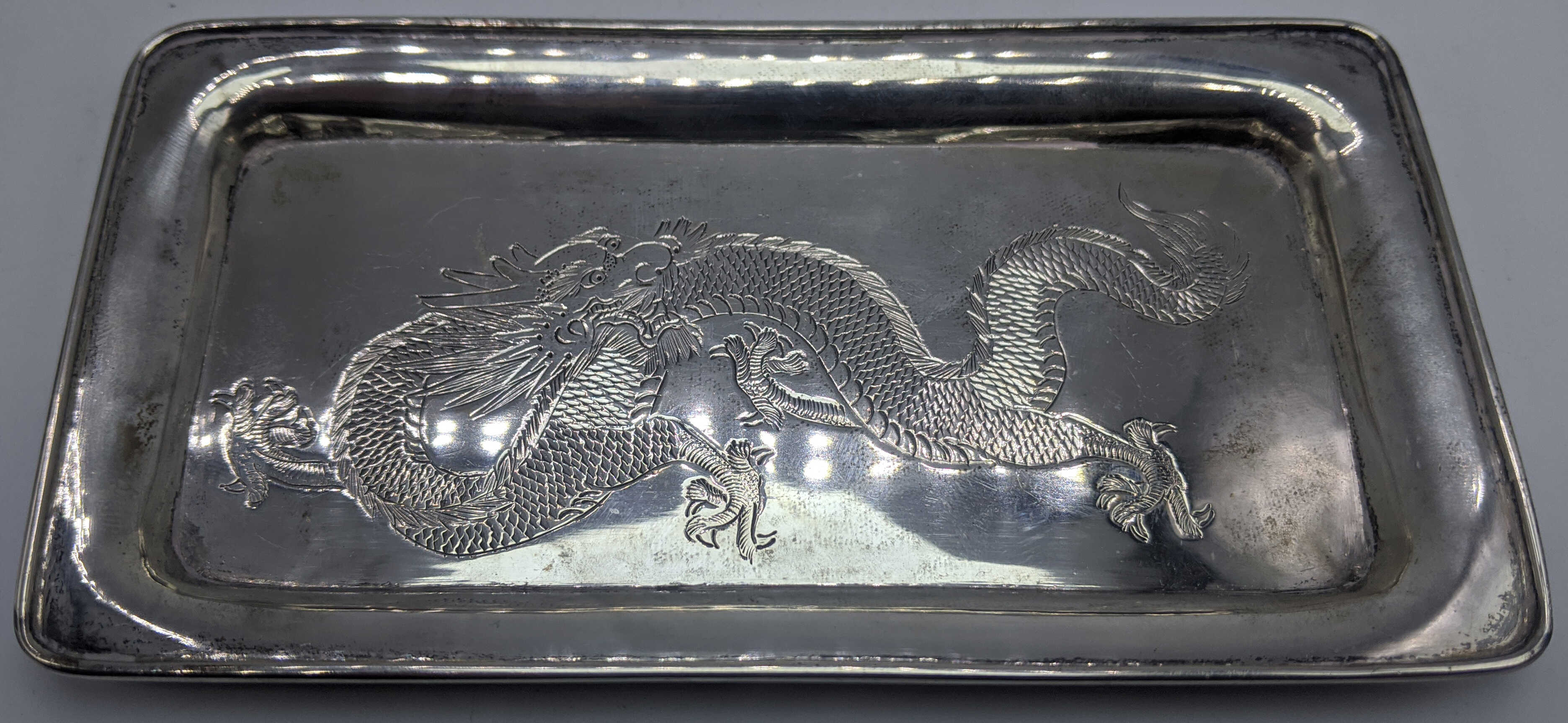 A Chinese silver pin dish, dragon embossed to lid, gilt interior, raised on three paw feet, marked