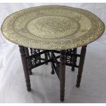 A late 19th/ early 20th century Indian folding table with brass top embossed with decor of flora and