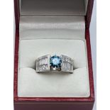 A white gold, treated blue diamond and diamond ring, claw set with the circular cut treated blue