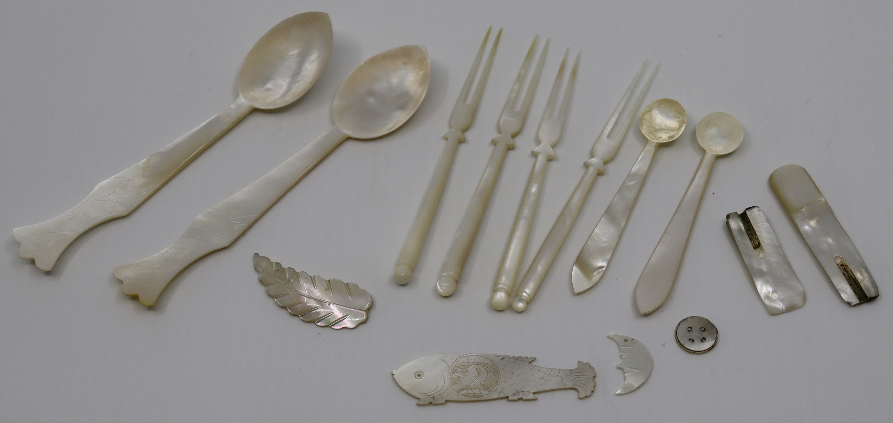 A collection of mother of pearl spoons, forks, Chinese gaming counters and others.