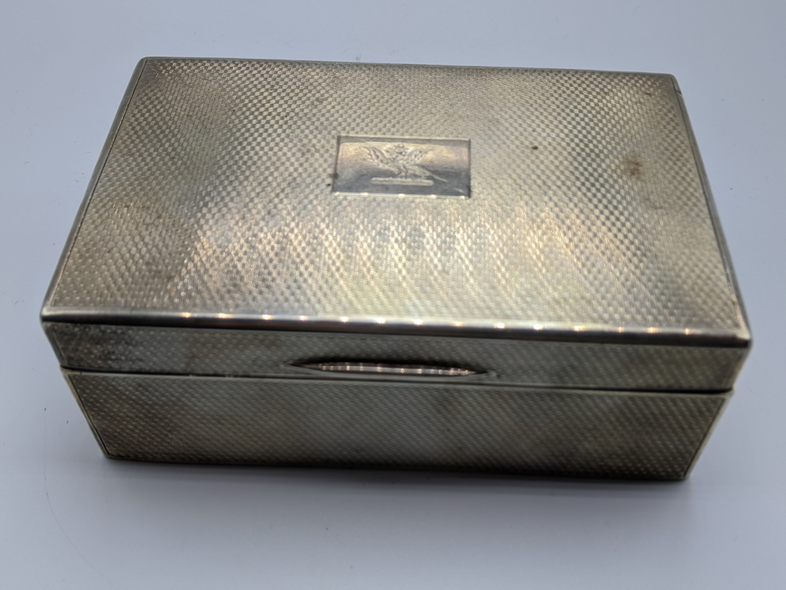 An early 20th century silver cigar case, engine turned outer, dragon crest, hallmarked London 1926-