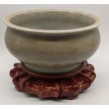 A Chinese 19th century celadon crackle glazed bowl, later hardwood stand, H.10cm D.21cm