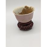A Chinese pink glazed miniature cup, Kangxi mark to base, later hardwood stand, H.4cm