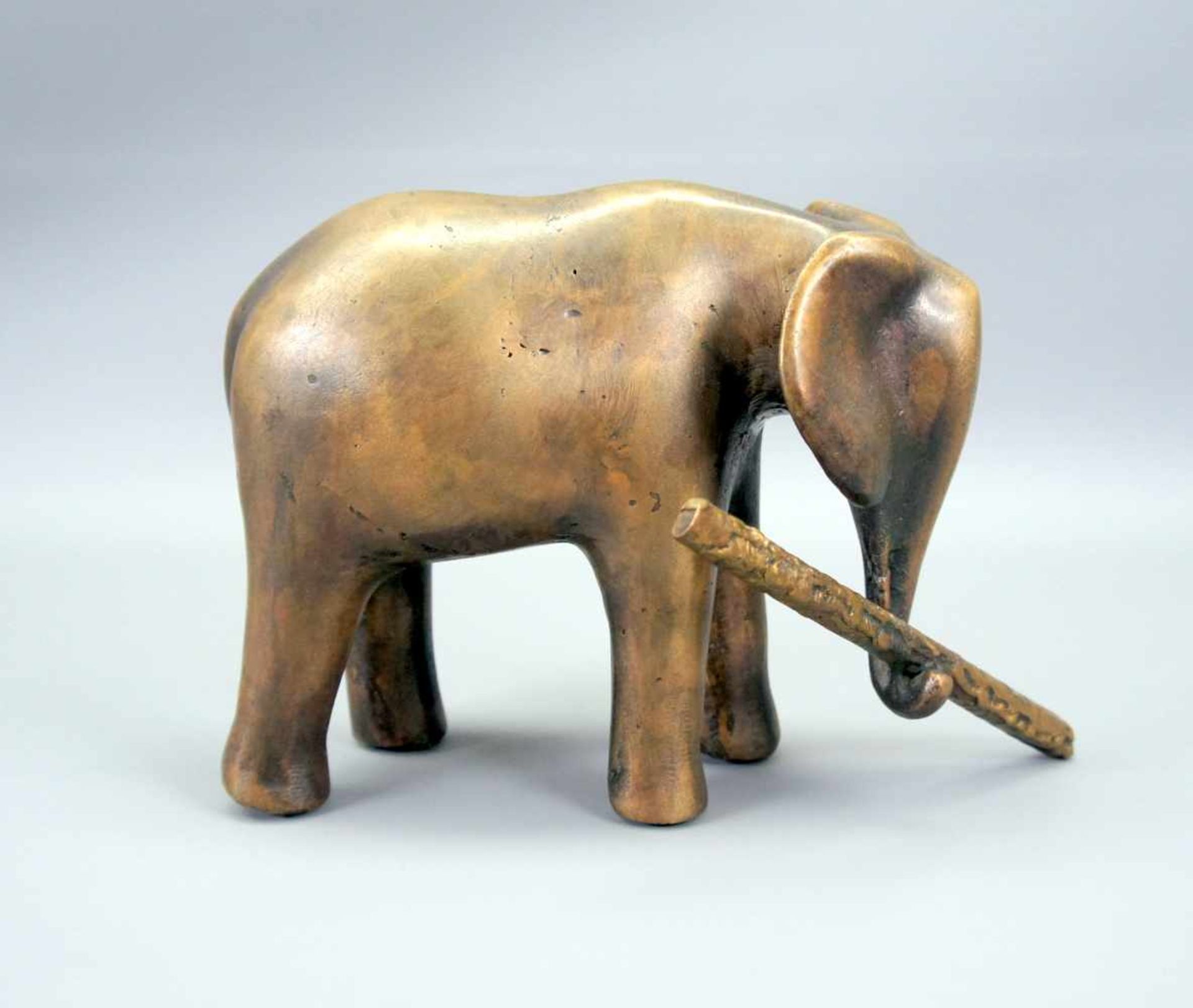 Elefant mit AstBronze, goldbraun patiniert. Vereinfacht dargestellter Elefant, einen Ast mit
