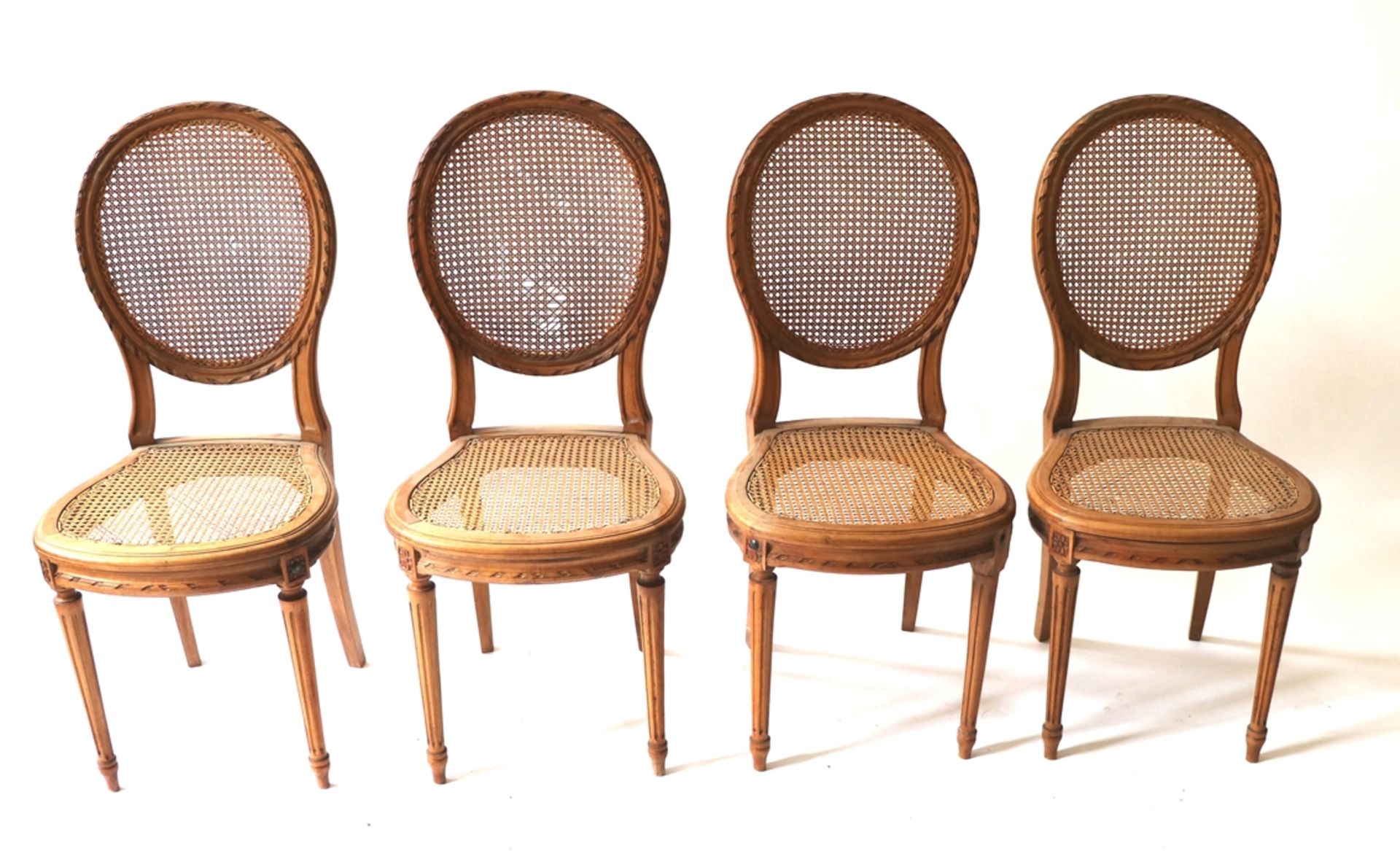 4 Stühle, Frankreich um 1900Nußbaum. Sitz und Rückenlehne mit Rohrgeflecht. Gestell mit Schnitzerei.