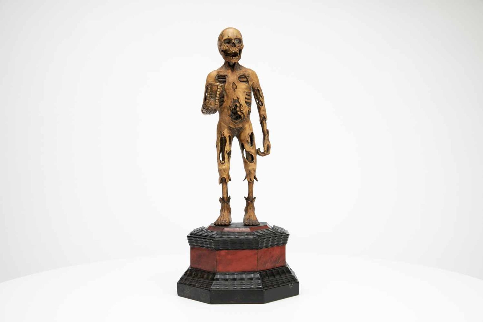 Wood carving of a small death figure with an hourglass