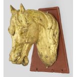 PferdekopfZinkguss, goldbronziert bzw. vergoldet. Montiert auf trapezförmiger Wandplatte aus rot