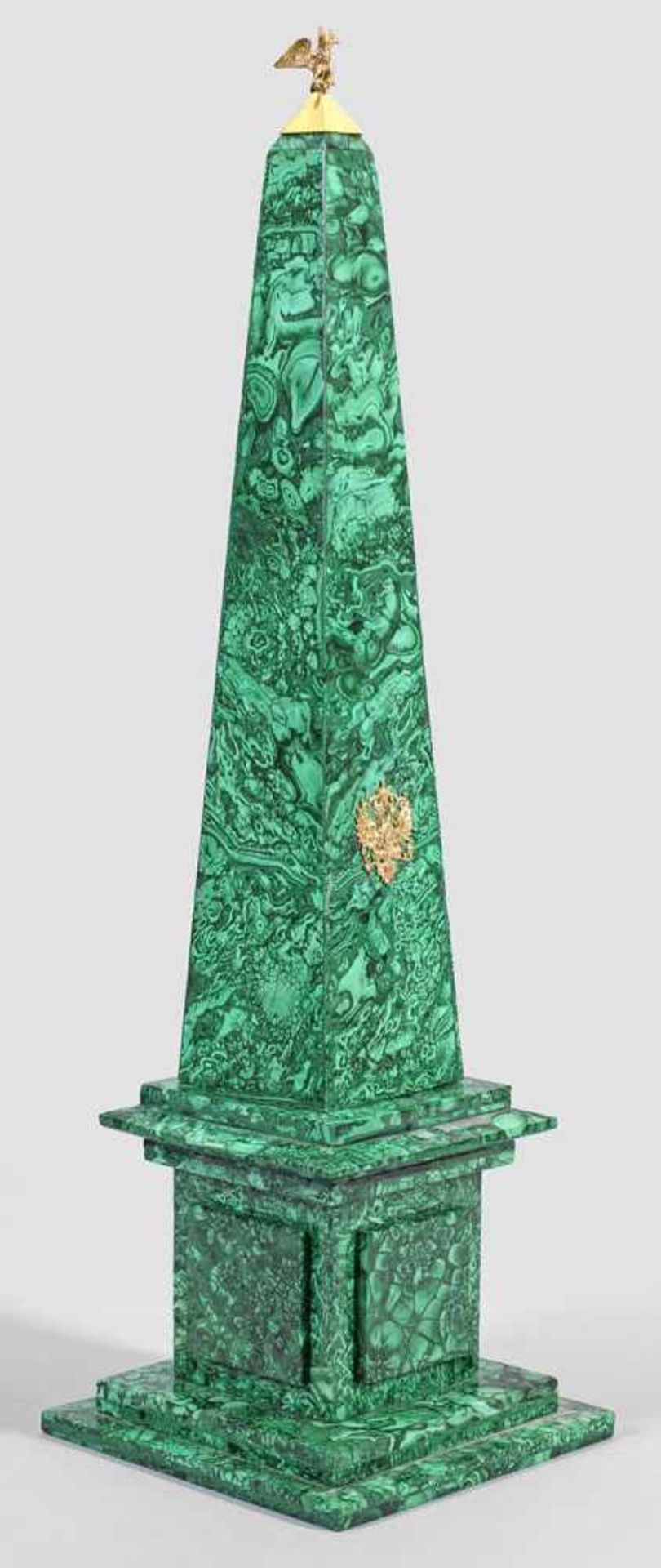 Malachit-ObeliskMalachit, poliert und Silber, vergoldet. Über getrepptem Stand würfelförmiger Sockel