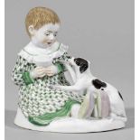 Kind mit HundAuf ovalem Sockel sitzendes kleines Kind in langem, grün gemustertem Kleid mit einem