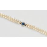 A pearl necklace with a diamond and sapphire claspA two-stranded necklace of 75/79 graduated