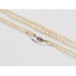 A French pearl necklace with a diamond and rubelite claspA two-stranded pearl necklace comprised