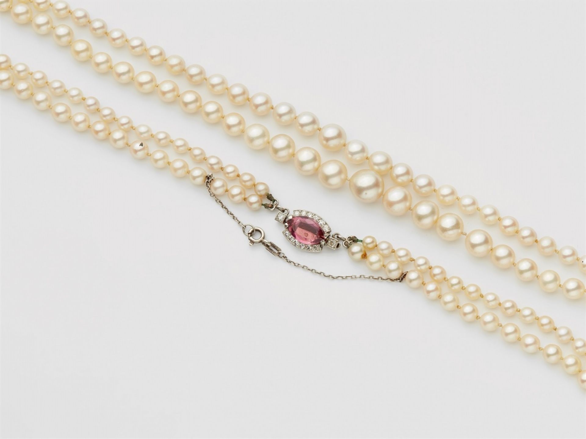 A French pearl necklace with a diamond and rubelite claspA two-stranded pearl necklace comprised