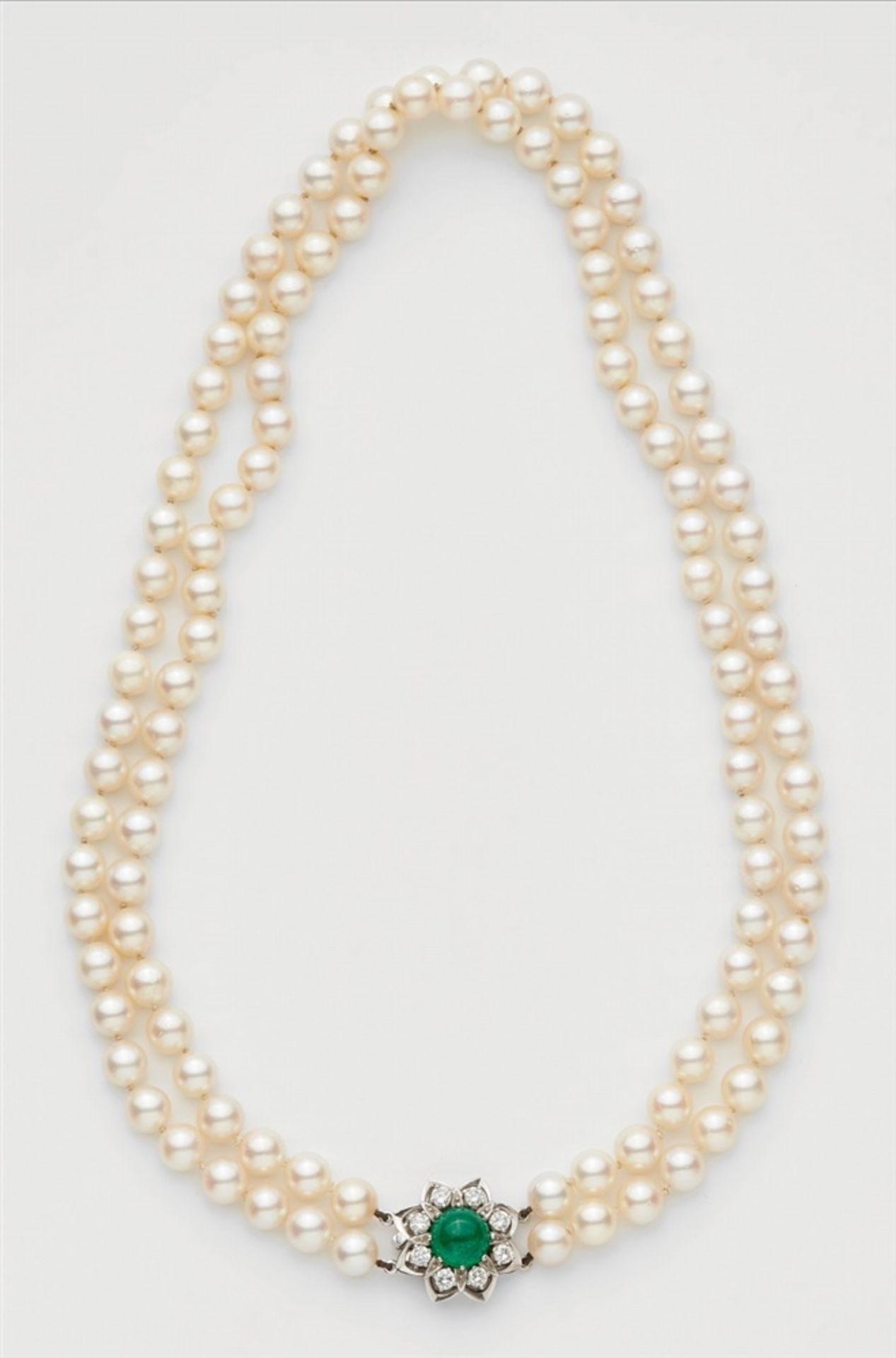 A cultured pearl necklace with an 18k gold diamond and emerald clasp.A two-stranded necklace of 54/