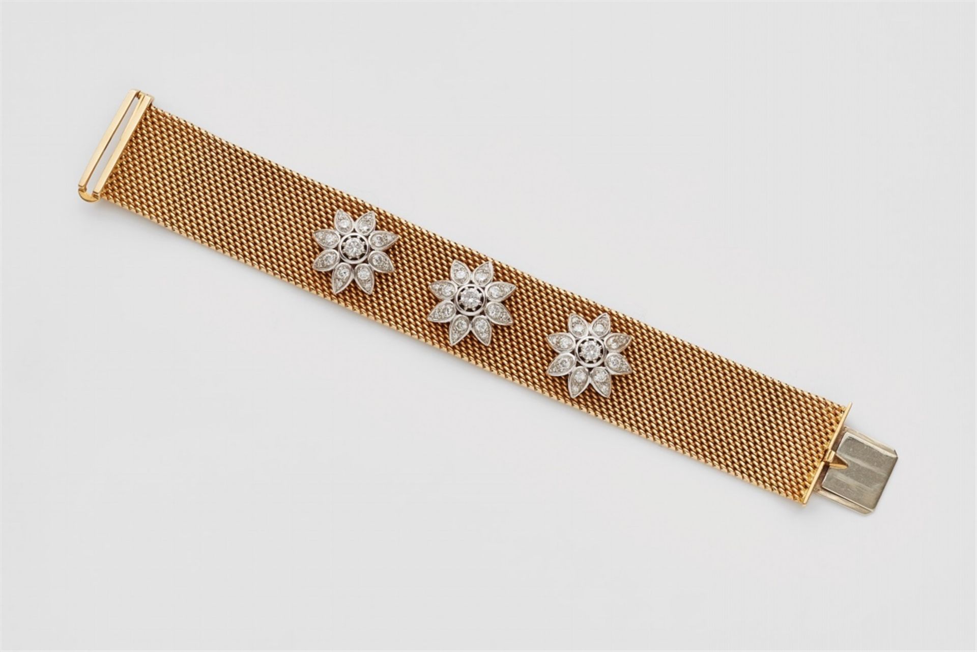 An 18k gold and diamond braceletDesigned as a flexible milanaise band with three floral white gold