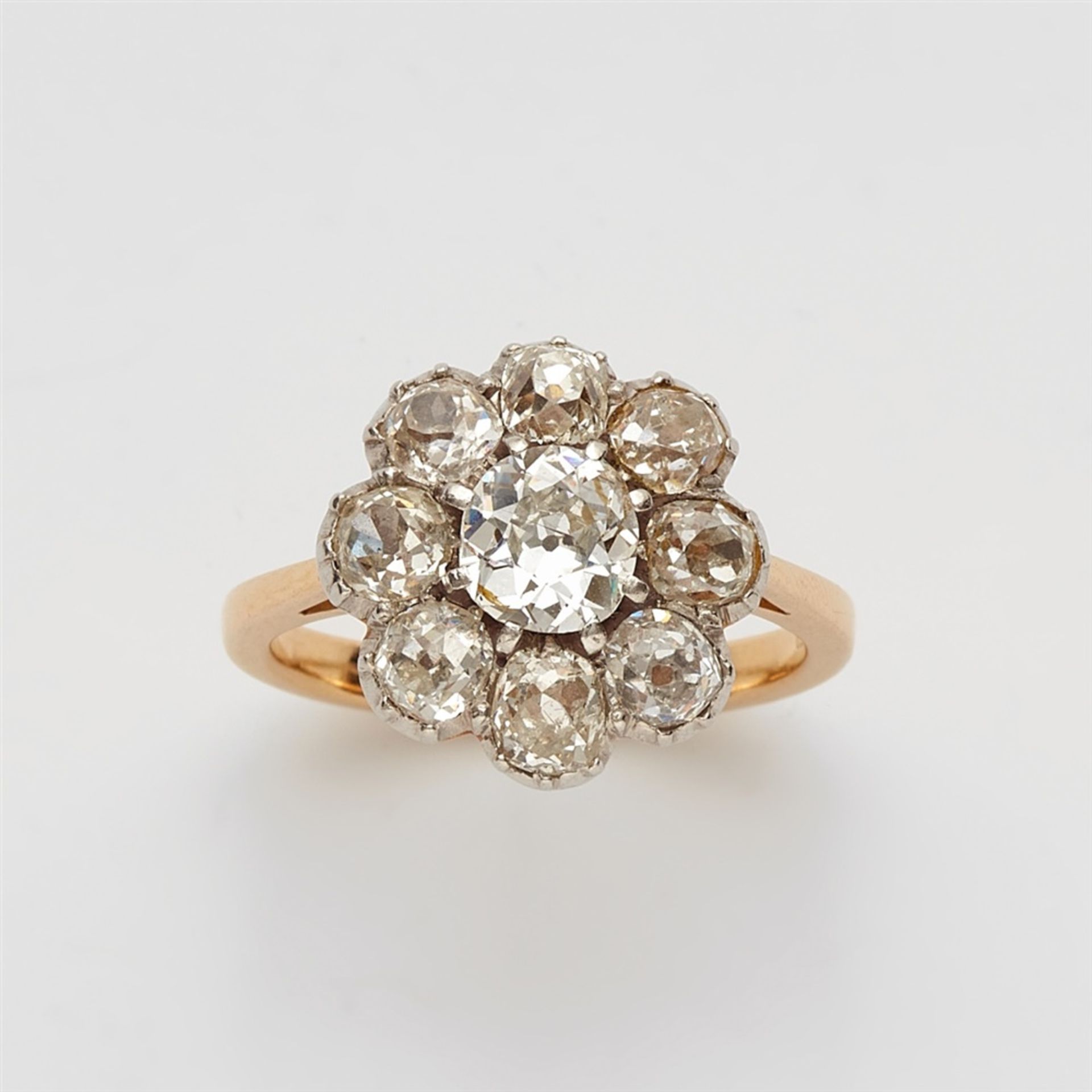 An 18k gold and diamond cluster ringThe bezel cluster set with nine cushion shaped old-cut