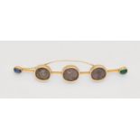 A jewelled 18k gold pin brooch with Roman silver coinsSlightly curved forged wire pin set with three